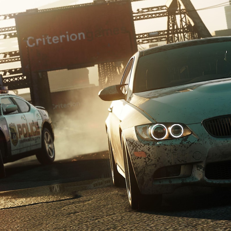 May include: A light-colored sports car speeds down a road, with a police car in pursuit. The image has a gritty, action-packed feel, with the word "Criterion" visible on a sign in the background.