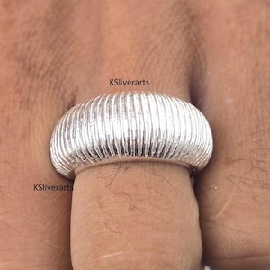 以下が含まれることがあります： リブ編みのデザインが施されたシルバーリングのクローズアップ。指にはめています。「KSliverarts」の文字が画像に表示されています。