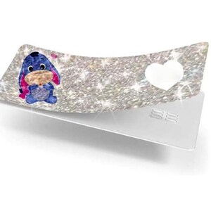 May include: A decorative, curved tray with a glittery silver surface. The tray features a cartoon image of Eeyore, a white heart, and a silver base. The Eeyore image is blue, pink, and tan.