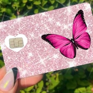 Puede incluir: Una tarjeta rosa brillante con un dise&ntilde;o de mariposa rosa brillante. La tarjeta tiene un recorte en forma de coraz&oacute;n blanco con un chip. La mariposa tiene detalles negros en sus alas.