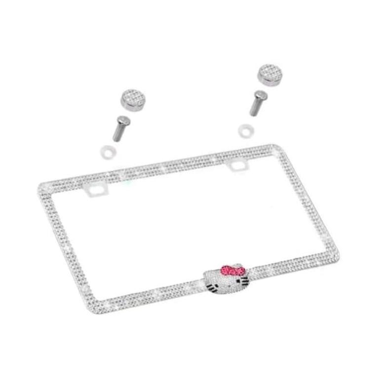 May include: A silver license plate frame encrusted with rhinestones. The frame features a Hello Kitty design with a pink bow. Includes mounting hardware.