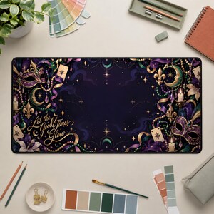 Può includere: Un tappetino da scrivania rettangolare con sfondo viola scuro, decorato con maschere di Mardi Gras, gigli, lune crescenti e perline nei colori oro, verde e viola. Il testo "Let the Good Times Glow" è scritto in caratteri dorati sulla sinistra.