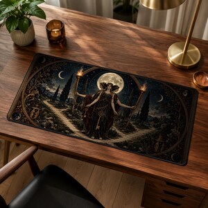 Può includere: Un tappetino da scrivania rettangolare con un'illustrazione scura e dettagliata di una figura a tre teste che regge torce fiammeggianti e chiavi. La scena è ambientata di notte sotto la luna piena, circondata da cipressi e bordi dorati.