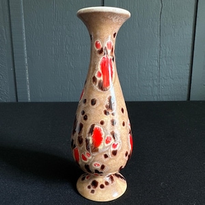 Könnte beinhalten: Eine Keramikvase mit beigefarbenem Sockel und ausgestelltem Oberteil. Die Vase ist mit roten und braunen abstrakten Mustern verziert. Die Vase ist etwa 18 cm hoch und eignet sich zum Präsentieren von Blumen oder als dekoratives Stück.