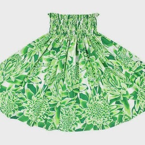 Puede incluir: Falda con estampado floral verde y blanco. La falda presenta una cintura fruncida y un diseño amplio y fluido. La tela está estampada con grandes flores verdes estilizadas sobre un fondo blanco.