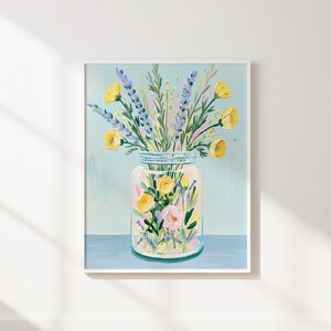 May include: A framed floral art print featuring a clear jar filled with yellow and pink flowers, and lavender sprigs. The jar sits on a blue surface against a light blue background. The artwork is in a white frame.