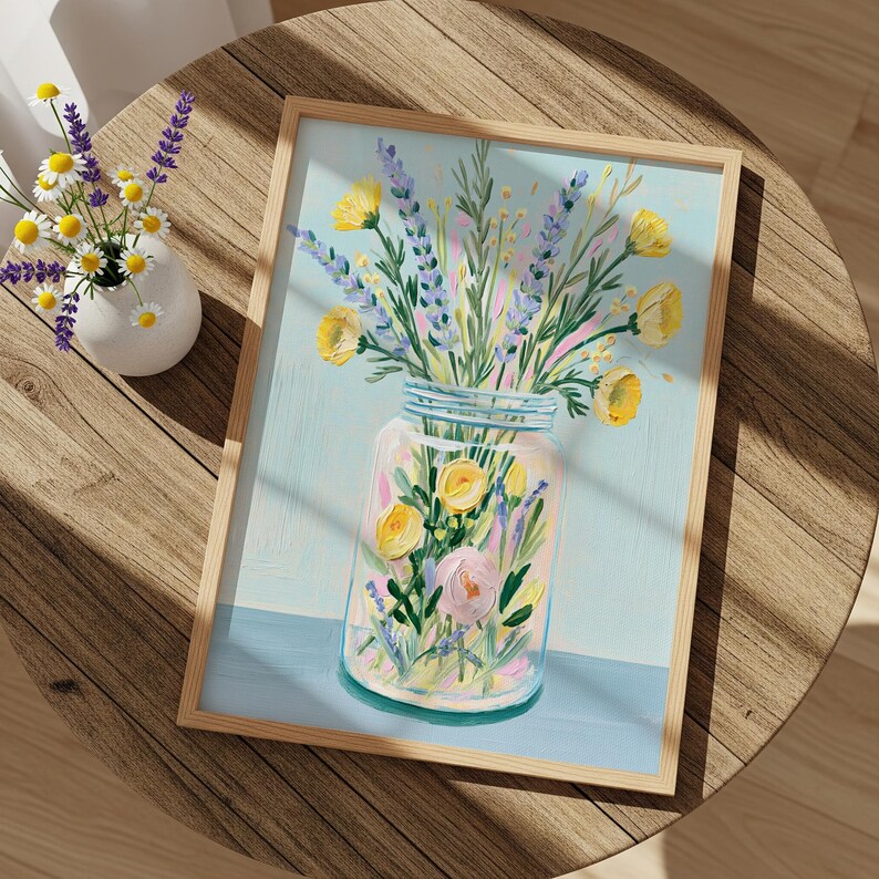 May include: A framed floral painting featuring a mason jar filled with yellow and pink flowers, and lavender sprigs. The painting has a light blue background and is set on a wooden table. A small vase with daisies and lavender is also on the table.