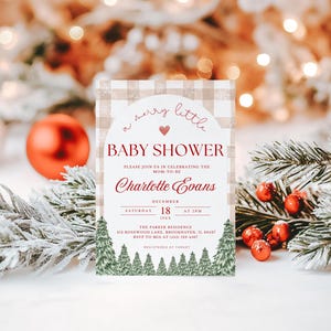 K&ouml;nnte beinhalten: Eine Babyparty-Einladung mit weihnachtlichem Thema. Die Einladung zeigt den Text "a merry little BABY SHOWER" in roter Schrift, zusammen mit dem Namen "Charlotte Evans". Die Einladung ist mit einem Karomuster und immergr&uuml;nen B&auml;umen verziert.