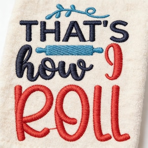 May include: Cream-colored kitchen towel with embroidered text: "THAT'S how I ROLL." The text is in navy blue and red, with a blue rolling pin graphic. A decorative blue flourish is above the word "THAT'S".