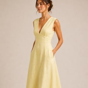 Puede incluir: Un vestido midi sin mangas en tono amarillo p&aacute;lido, con escote en V profundo, cuerpo ajustado y falda acampanada con bolsillos laterales. El vestido presenta una silueta limpia y estructurada que llega hasta la altura de la pantorrilla.