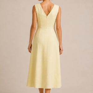 Puede incluir: Un vestido midi sin mangas de color amarillo p&aacute;lido con escote en V en la espalda, cuerpo entallado con cintura definida y falda acampanada en forma de A que llega por debajo de las rodillas. La prenda incluye una cremallera vertical central.