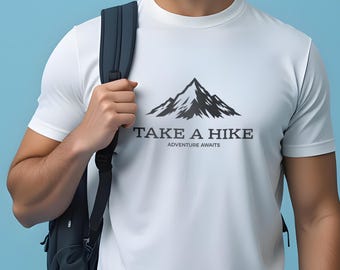 May include: White t-shirt with a mountain graphic and the text "TAKE A HIKE, ADVENTURE AWAITS" in gray. The shirt is made of a soft, comfortable material.