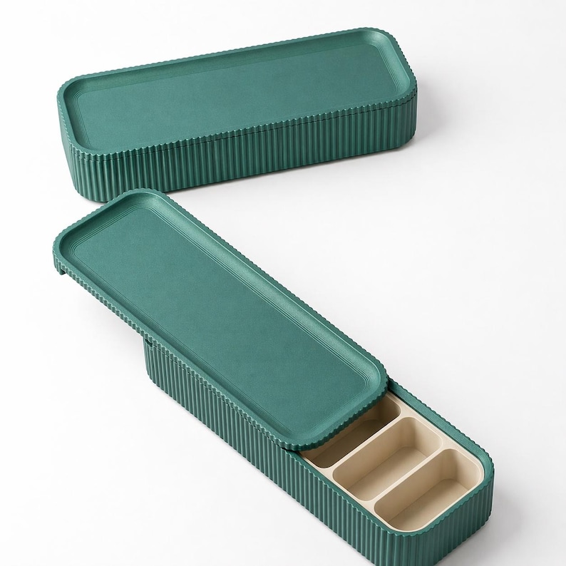 Two Green ribbed storage trays, one with sliding lid, featuring a light white oak compartment insert inside the other closed.
