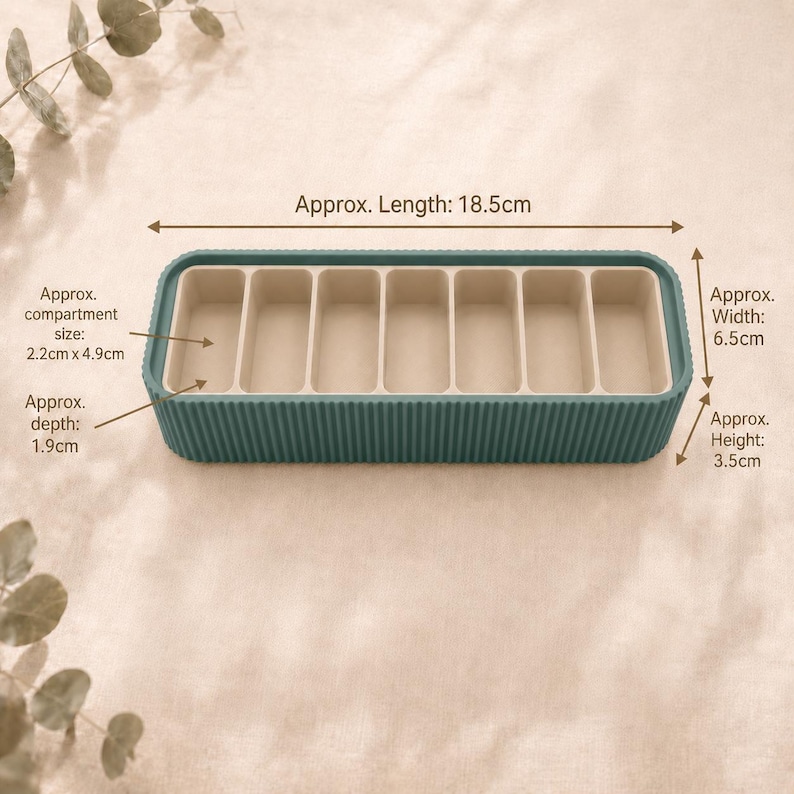 Oxide Green Metallic and beige large pill case shown open, with approximate length, width, height, compartment size and depth measurements labelled on a soft neutral background.