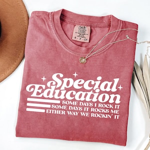 May include: A dusty rose crewneck t-shirt featuring white screen-printed text that reads Special Education, Some days I rock it, Some days it rocks me, Either way we rockin' it, accented with small star icons and a Comfort Colors brand label.