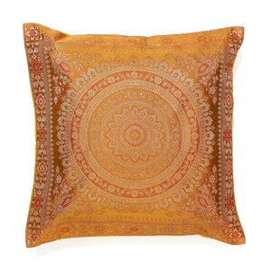 May include: Mustard yellow square cushion featuring an elaborate, circular mandala design in shades of orange and gold. The cushion has a detailed border with floral and geometric patterns, suitable for home decor.