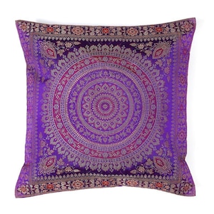 May include: Square purple pillow with a detailed mandala design in shades of pink and gold. The pillow has a decorative border with floral patterns and is likely made of a soft fabric.