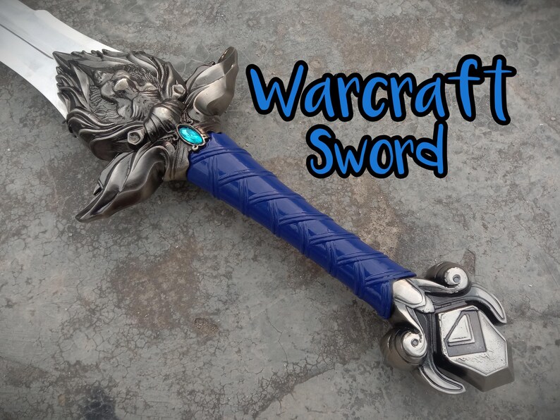 May include: A detailed sword with a silver blade and ornate hilt. The hilt features a blue grip and a decorative design with a teal-colored gem. The text "Warcraft Sword" is written in blue.