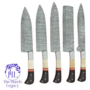Peut inclure: Cinq couteaux de cuisine en acier de Damas avec des lames à motifs. Les manches sont noirs avec un accent blanc et rouge. Le logo "The Hands Legacy" est dans le coin inférieur gauche.