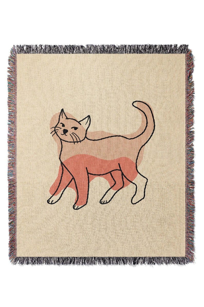 K&ouml;nnte beinhalten: Beige Decke mit einer Katzenillustration. Die Katze ist schwarz umrandet mit Pfirsich- und Korallent&ouml;nen. Die Decke hat einen Fransenrand mit verschiedenen Farben.