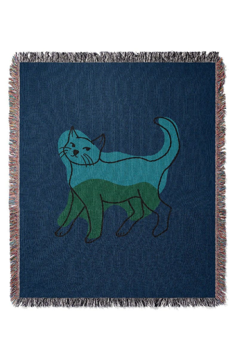 K&ouml;nnte beinhalten: Marineblaue Decke mit einem stilisierten Katzendesign. Die Katze ist in T&uuml;rkis- und Gr&uuml;nt&ouml;nen mit schwarzen Umrissen dargestellt. Die Decke hat einen Fransenrand.