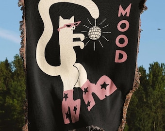 May include: Black throw blanket with a white cat wearing pink sunglasses and holding a disco ball. The blanket has pink text that says "MOOD" and pink star shapes. The blanket has a fringed edge.