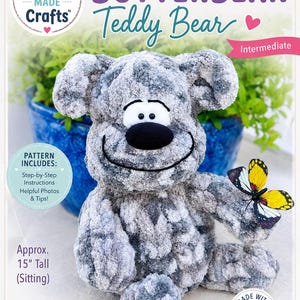 May include: A gray and white Butterbean teddy bear, approximately 15 inches tall when sitting, with a smiling face and a black nose. The image includes text that says "Pam Made Crafts" and "Butterbean Teddy Bear". A yellow and black butterfly is attached to the bear.