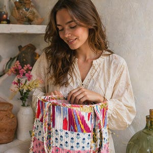 Puede incluir: Un bolso tote colorido con un diseño de patchwork. El bolso presenta una variedad de patrones y colores, incluyendo rosa, azul y blanco. El bolso tiene una textura acolchada y asas resistentes.