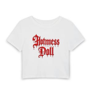 以下が含まれることがあります： ゴシック体の赤い「Hotmess Doll」の文字がプリントされた白いクロップドトップ。 文字は滴るような効果があります。 このシャツは半袖で、クルーネックです。
