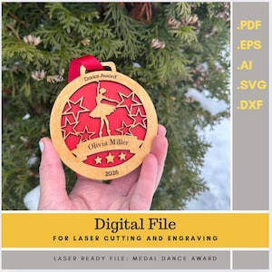 Puede incluir: Una medalla de madera con interior rojo y marco dorado, con una silueta de bailarina y recortes de estrellas. La medalla dice "Dance Award" y "Olivia Miller 2026". Se adjunta una cinta roja para colgar. La imagen también incluye el texto "Digital File for Laser Cutting and Engraving".