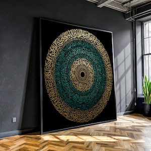 May include: Large framed artwork featuring a circular design with intricate calligraphy in gold and teal against a black background. The artwork is displayed in a modern room with a dark wall and wooden floor.