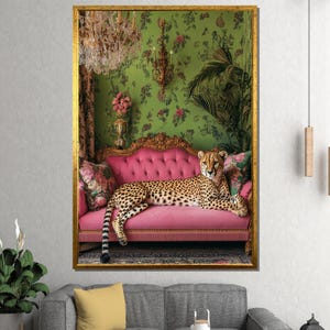 May include: A framed print showing a cheetah reclining on a pink sofa. The background features green floral wallpaper, a chandelier, and decorative elements. The artwork is enclosed in a gold frame, enhancing its opulent appearance.