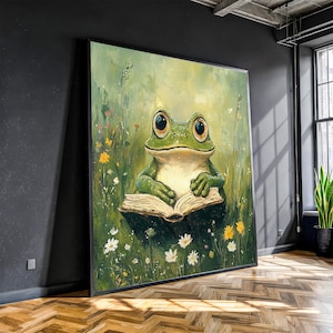 Puede incluir: Una impresión artística enmarcada de una rana verde con ojos grandes, leyendo un libro en un campo de flores silvestres. La rana es el punto focal, sobre un fondo de tonos verdes y amarillos. La obra de arte se exhibe en una habitación con una ventana y una planta.