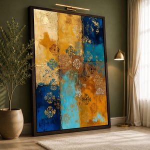 May include: Abstract wall art in a dark wood frame. The artwork features a textured design with gold, blue, and yellow hues. Decorative floral patterns are layered throughout the piece. The artwork is leaning against a green wall.