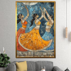 May include: A framed painting shows three women in traditional dress, dancing with raised arms. They wear orange, yellow, and blue skirts, with detailed jewellery and headwear. The background is a textured blue with a moon, all within a gold frame.