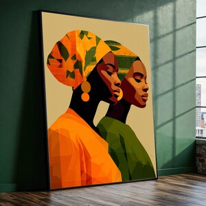 May include: A framed art print featuring two women in profile. One woman wears an orange head wrap and top, the other a green top and head wrap. Both have gold earrings. The artwork has a warm color palette and a modern, stylized aesthetic.