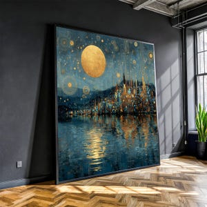 May include: Large framed artwork depicting a nighttime cityscape reflected in water. The painting features a large golden moon, gold and teal lights, and a dark blue sky. The artwork is displayed in a room with a dark wall and a wooden floor.