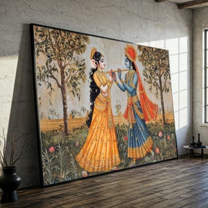 Op de afbeelding: Groot ingelijst kunstwerk met twee figuren in traditionele Indiase kleding. Eén figuur draagt ​​geel, de ander blauw, beide met een fluit. De achtergrond toont bomen, bloemen en een hek, met een neutraal kleurenpalet.