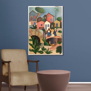 Puede incluir: Una impresi&oacute;n art&iacute;stica enmarcada que representa una colorida escena de un pueblo. La obra presenta casas estilizadas en tonos rojos, azules y amarillos, con figuras de personas y exuberante follaje verde. La pintura se exhibe en una pared azul.