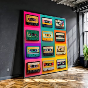 Op de afbeelding: Een groot ingelijst kunstwerk met een raster van twaalf kleurrijke cassettes. Elke tape heeft een uniek kleurenschema, met levendige tinten roze, groen, geel en paars. Het kunstwerk wordt getoond tegen een donkergrijze muur in een kamer met een raam.