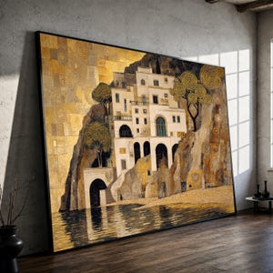 May include: A large rectangular wall art print featuring a stylized coastal scene with a white multi-story building nestled into a rocky cliffside. The composition uses a palette of gold, brown, and cream, with swirling tree motifs and water reflections.