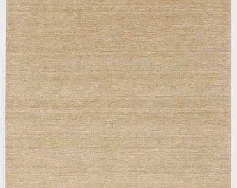 May include: A rectangular, beige rug with a textured surface. The rug has a simple design and a fringe along the edges. The neutral colour and minimalist style make it suitable for various interior design styles.