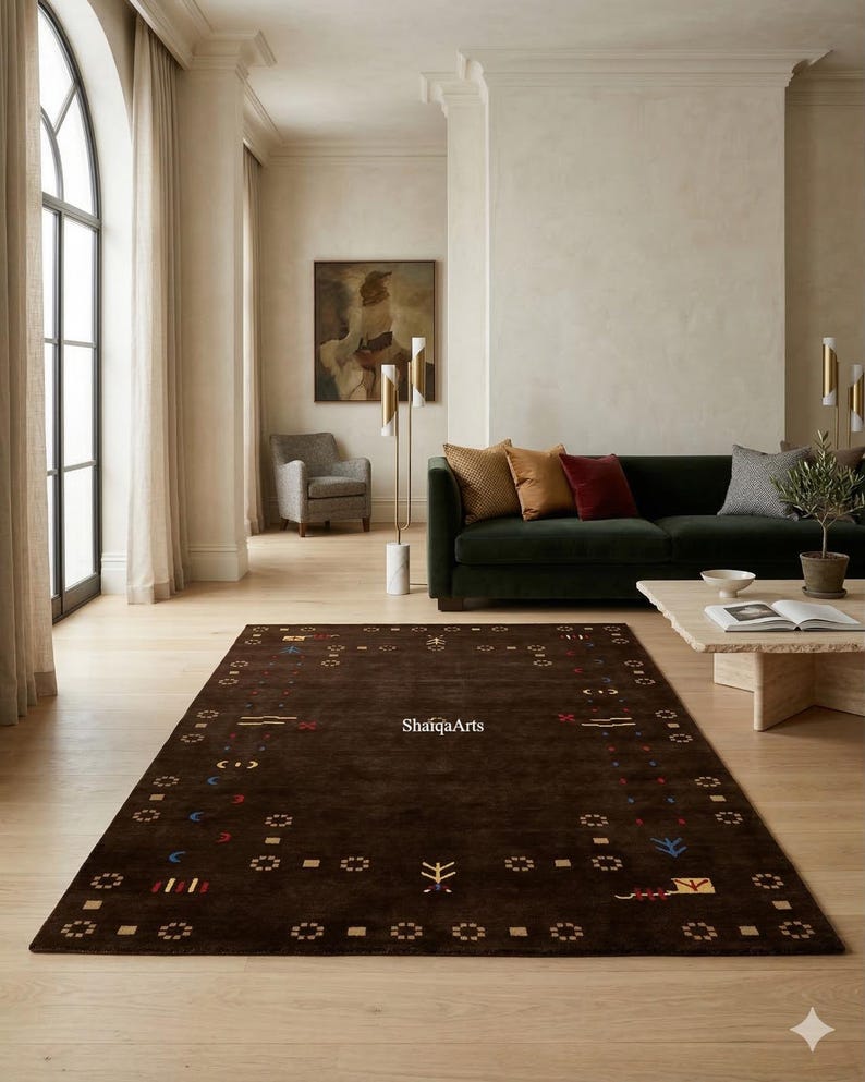May include: A rectangular, dark brown rug with a patterned border and scattered geometric designs in various colors. The rug is placed on a light-colored wooden floor in a living room setting. The text "ShaigaArts" is visible on the rug.