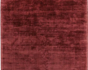 Puede incluir: Una alfombra rectangular grande en color burdeos oscuro. La alfombra tiene una apariencia suave y texturizada con sutiles variaciones de tono, creando una sensación rica y lujosa. El diseño es simple, con un enfoque en el color y la textura.