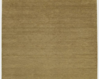 May include: A rectangular, olive-green rug with a textured surface. The rug has a simple, minimalist design and a soft, inviting appearance. The edges of the rug are slightly frayed, adding to its natural aesthetic.