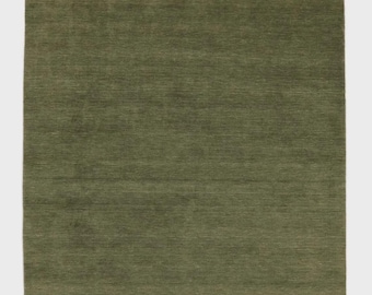 May include: A rectangular olive green rug with a textured surface. The rug has a solid color and a simple design, suitable for various interior styles. The rug's dimensions are not visible.