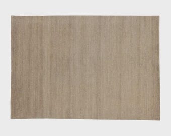 May include: A rectangular, neutral-toned rug with a woven texture. The rug's color is a light beige, and it appears to be made of natural fibers. The design is simple and minimalist, suitable for various interior styles.