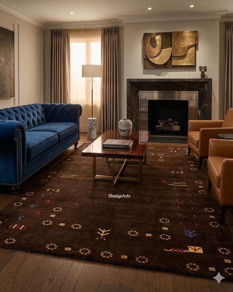 May include: A living room featuring a tufted blue velvet sofa, two brown leather armchairs, and a dark brown rug with a geometric pattern. A marble-based lamp and a dark wood coffee table are also present. A fireplace and artwork complete the scene.
