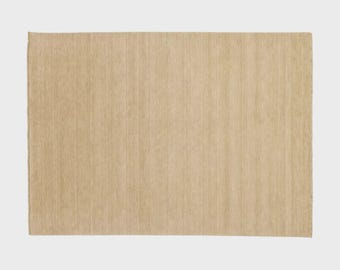 May include: A rectangular, light beige rug with a woven texture. The rug has a simple design and a neutral colour palette, suitable for various interior styles. The rug's dimensions are not visible.