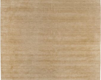 May include: A rectangular beige rug with a simple, textured design. The rug has a soft, neutral colour and a subtle pattern, suitable for various interior styles. The edges have a fringed detail.